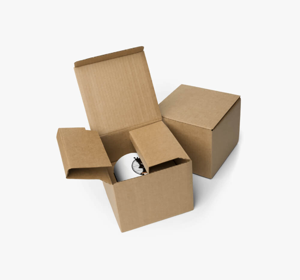 Two cardboard boxes with a white mug inside one, partially visible showing a black silhouette design, highlighting secure packaging.
